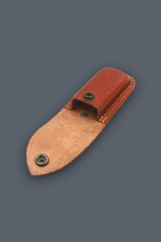 A small leather sheath or pouch made of two-toned brown leather with brass-tone snap fasteners, shown on a plain dark gray background.