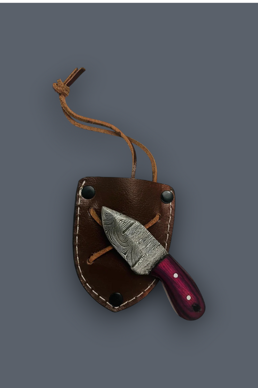 A fixed-blade knife with a patterned steel blade and a dark purple handle, tucked inside a brown leather sheath with a tan lanyard, shown on a solid dark gray background.