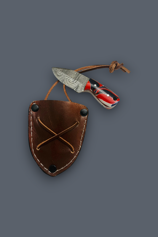 A folding pocket knife with a patterned steel blade and red-and-black handle, resting above a brown leather sheath on a plain dark gray background.