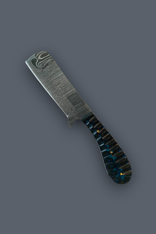 A Damascus steel folding knife with a patterned steel blade and a dark handle featuring blue, black, and gold inlay, shown on a solid dark gray background.