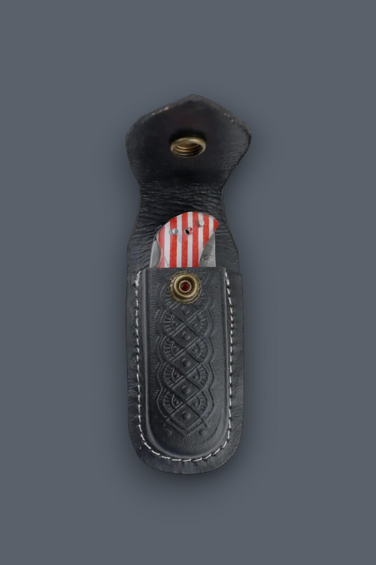 A black leather knife sheath with a stitched Celtic knot pattern and brass snap button, shown on a dark gray background with a knife partially inserted.