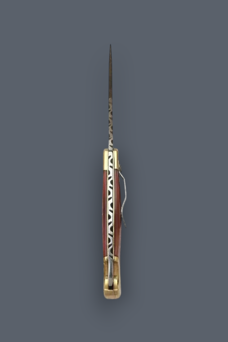 A vintage folding pocket knife with a patterned reddish-brown and white handle, a long steel blade, and brass hardware, shown vertically against a solid dark gray background.
