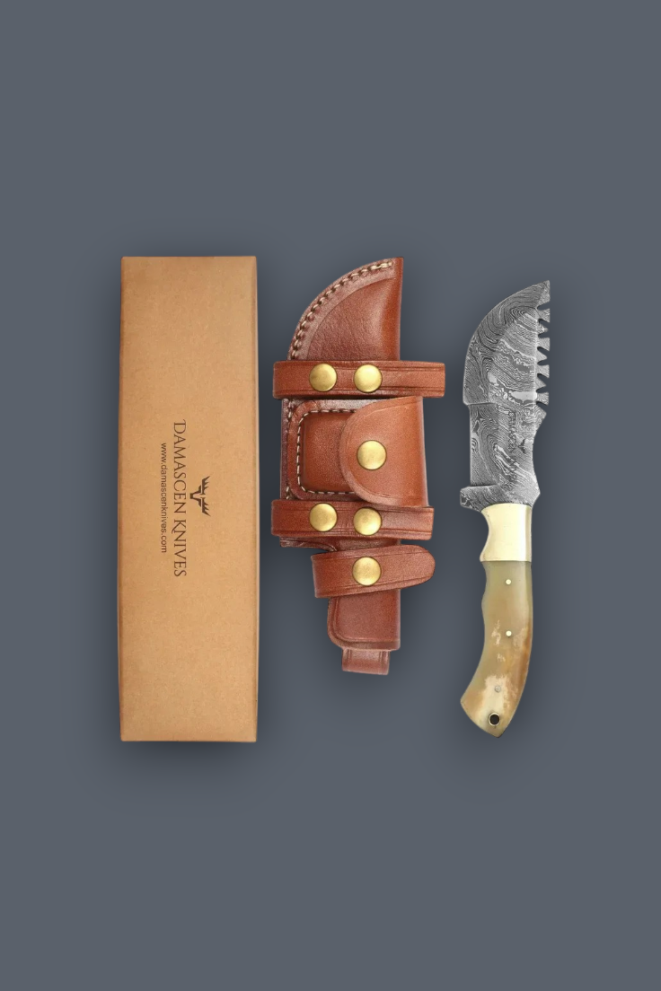 A fixed-blade knife with a patterned steel blade and bone handle is displayed next to its brown leather sheath and a tan presentation box on a dark gray background. The brand 'Daimlerfer Knife' is printed on the box.
