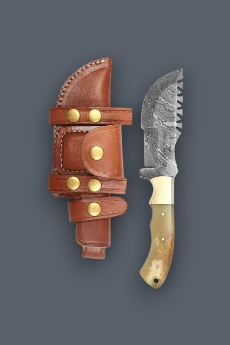 A fixed-blade knife with a patterned steel blade, cream handle, and brass rivets, shown next to its brown leather sheath with brass snap buttons on a dark gray background.