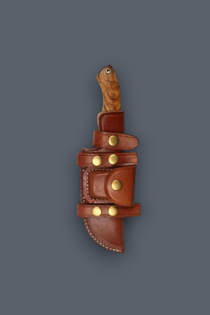 A brown leather knife sheath with brass snap buttons and a wooden-handled knife partially inserted, shown against a solid dark gray background.