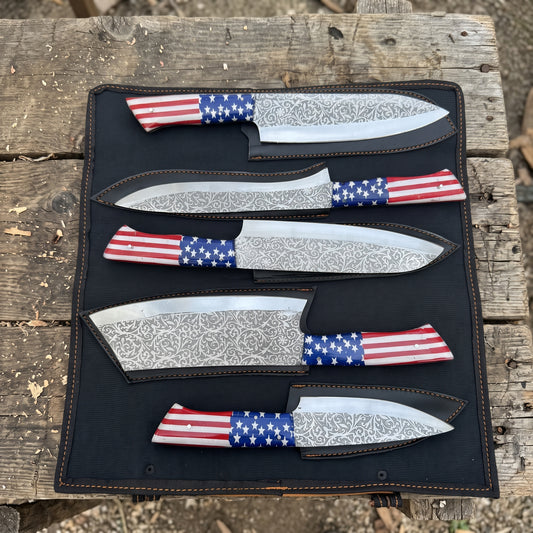 Five fixed-blade knives with patterned steel blades and red, white, and blue American flag wrapped handles, displayed in a black roll-up case on a rustic wooden surface.