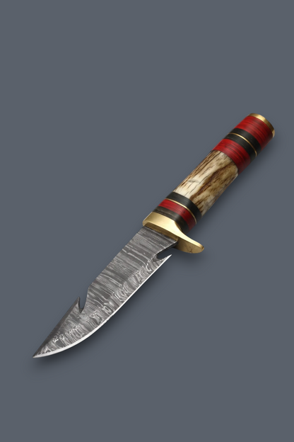 A custom fixed-blade knife with a patterned Damascus steel blade, a brass bolster, and a handle made of red, black, and natural wood inlay, shown on a solid dark gray background.
