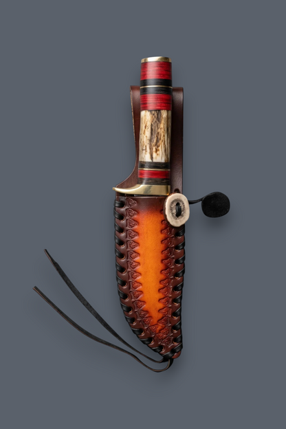 A handcrafted knife with a textured brown leather sheath, featuring a red and black striped handle, a natural wood inlay, and a brass guard, shown against a solid dark gray background.
