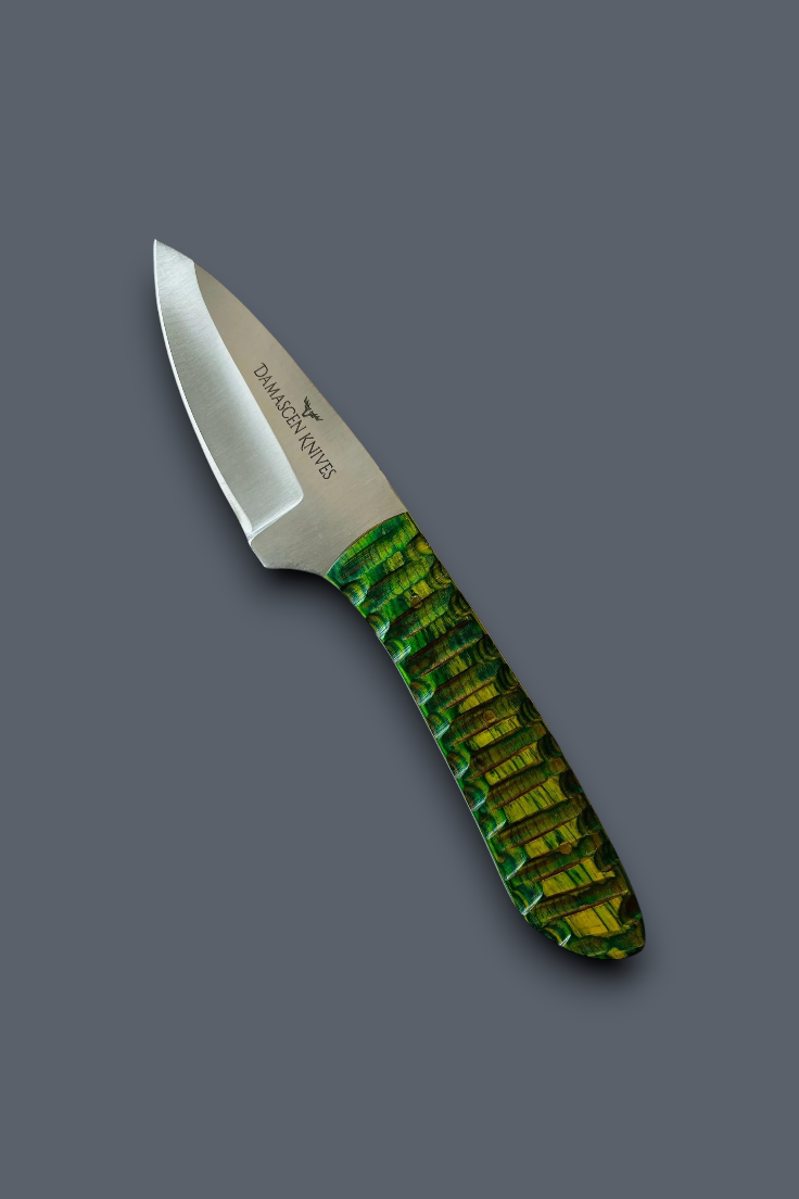 A fixed-blade knife with a satin-finished silver blade and a textured green handle, shown diagonally on a solid dark gray background. The brand 'Dakota Knife' is printed on the blade.