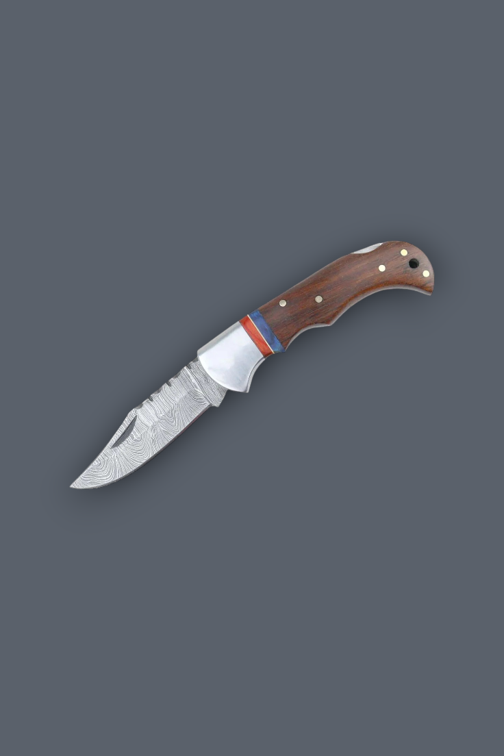 A folding pocket knife with a patterned steel blade, a silver bolster, and a brown wooden handle with brass rivets and a red and blue accent stripe, shown on a solid dark gray background.