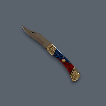 A folding pocket knife with a satin-finished steel blade and a decorative handle made of red and blue marbled wood with gold-toned metal accents, shown on a solid dark gray background.