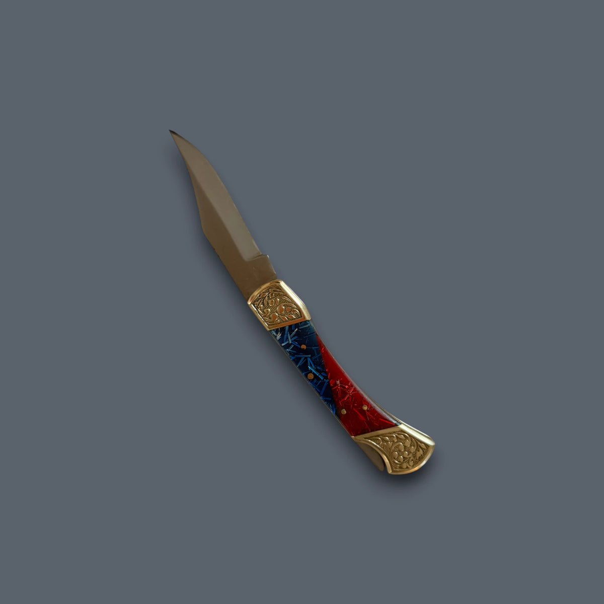 A pocket knife with a gold-toned blade and handle end caps, featuring a red and blue marbled inlay handle, shown on a solid dark gray background.