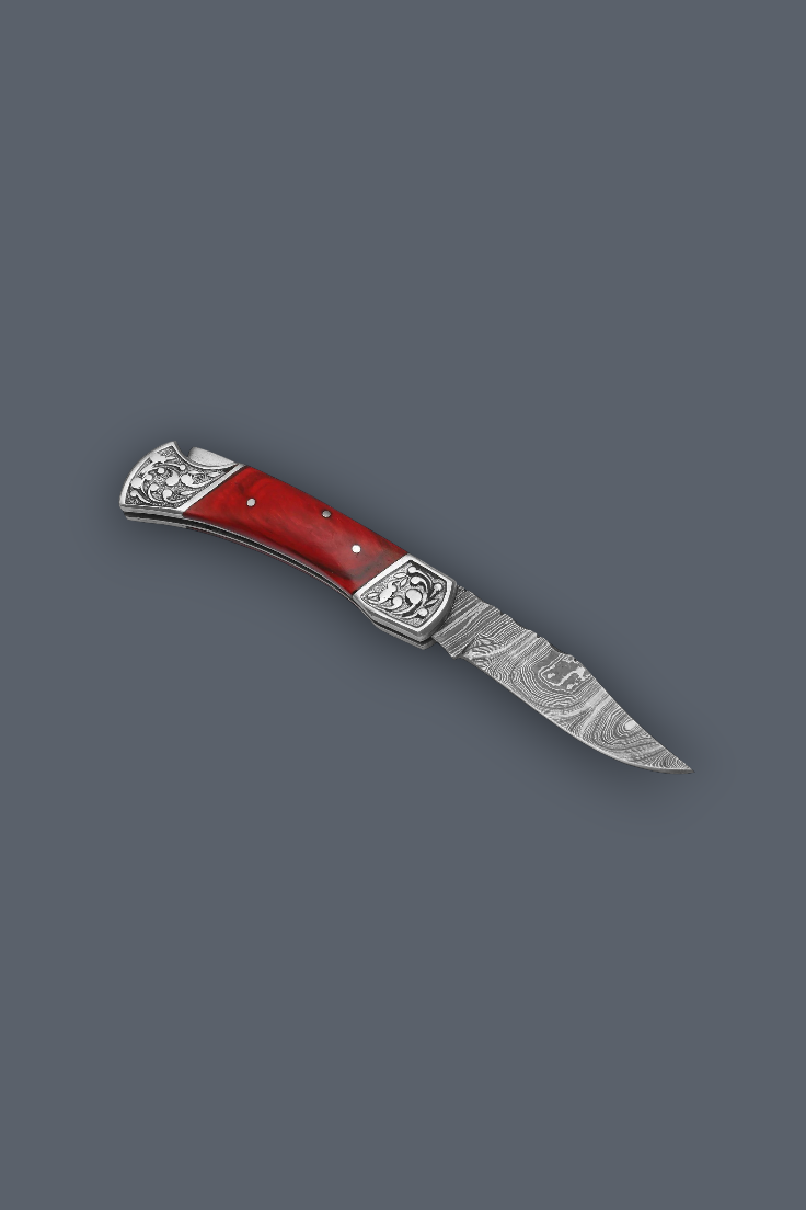 A folding pocket knife with a red handle and a patterned steel blade, shown diagonally on a solid dark gray background.