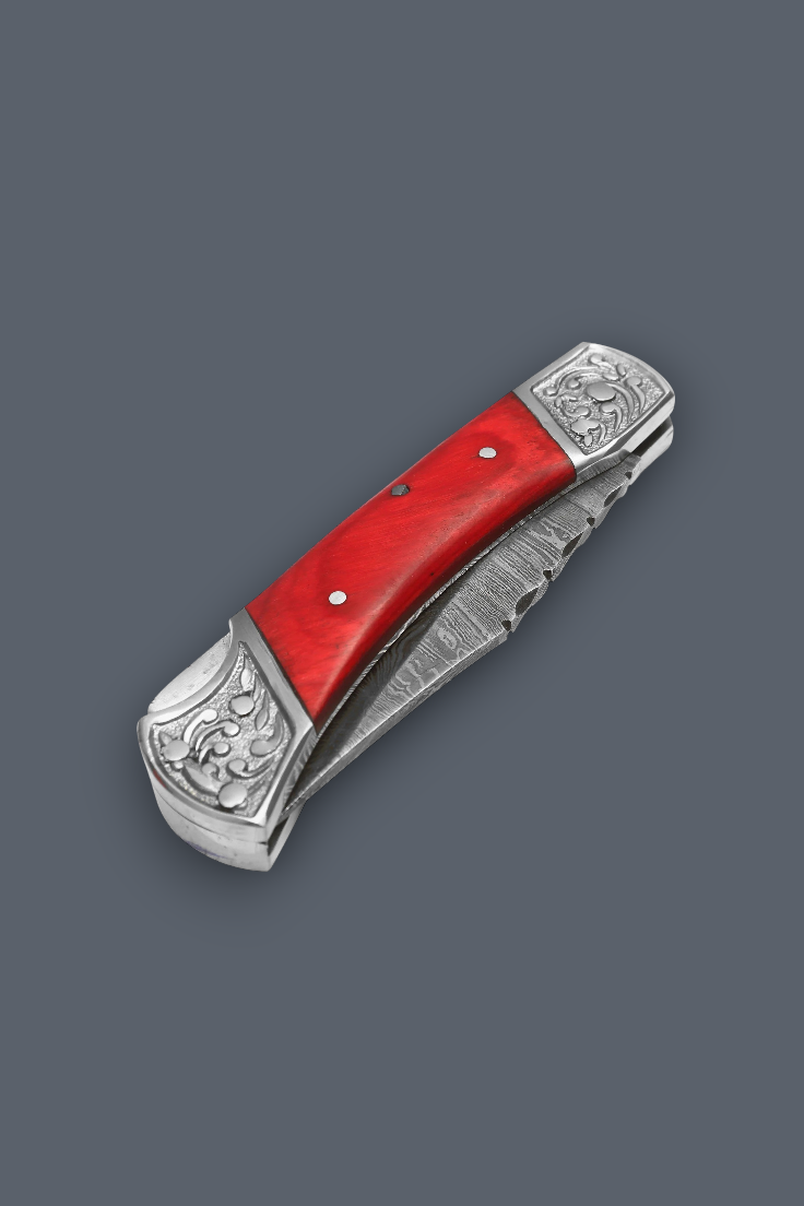 A folding pocket knife with a bright red handle scale and ornate silver-toned metal guard and bolster, shown open on a solid dark gray background.
