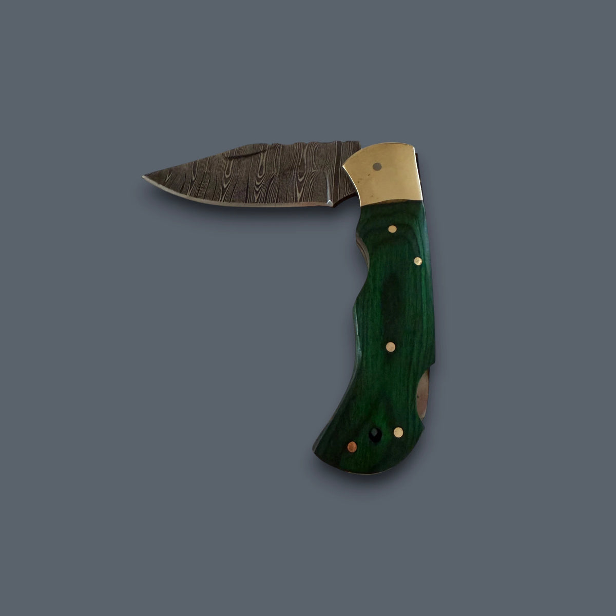 A folding pocket knife with a dark patterned steel blade, a brass bolster, and a green inlaid wooden handle, shown against a solid dark gray background.