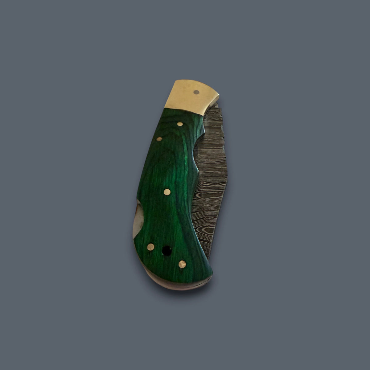 A folding pocket knife with a dark green marbled wood handle, gold-toned brass pins, and a partially visible Damascus steel blade, set against a solid dark gray background.