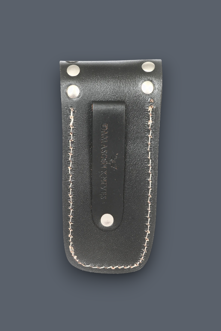A dark gray leather knife sheath with white stitching and silver metal rivets, featuring a central leather tab stamped with the brand name 'BLACK MANTLE'.