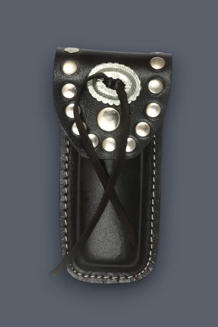 A black leather knife sheath with silver conchos and studs, featuring a braided black leather lanyard, shown against a solid dark gray background.