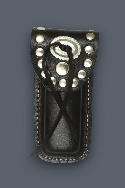 A black leather knife sheath with silver conchos and studs, featuring a braided black leather lanyard, shown against a solid dark gray background.