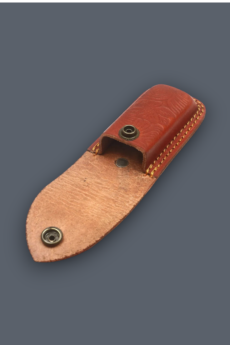 A small leather knife sheath or pouch made of two-toned brown leather with brass snap buttons, shown on a plain dark gray background.