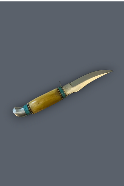 A traditional hunting knife with a curved yellow-bone handle, turquoise inlay bands, and a silver steel blade, shown on a solid dark gray background.
