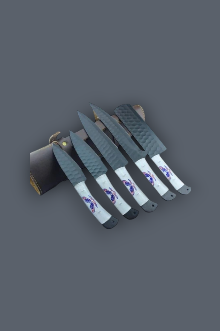 A set of five knives with textured gray blades and white handles featuring purple and blue graphic designs, displayed next to a dark leather sheath on a solid dark gray background.