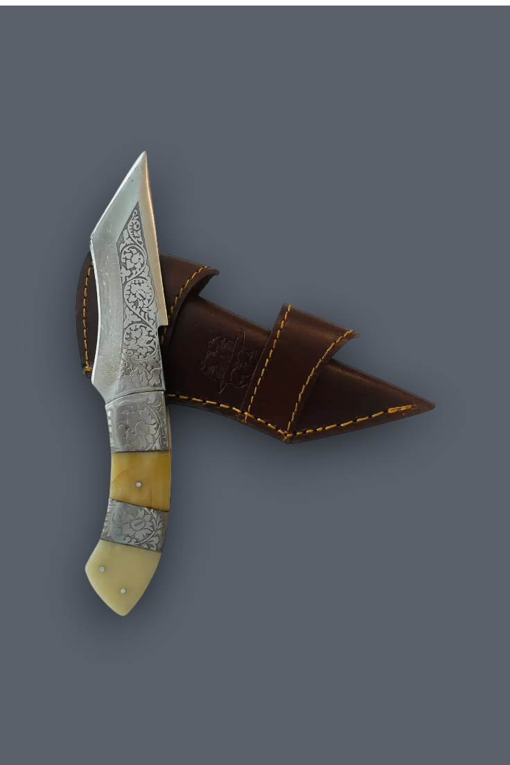 A decorative fixed-blade knife with a patterned steel blade, silver-toned metal bolster, and cream-colored handle scales, shown next to its brown leather sheath on a solid dark gray background.