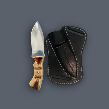A fixed-blade knife with a polished silver blade and a decorative tan and brown handle, shown next to a black leather sheath with white stitching on a solid dark gray background.