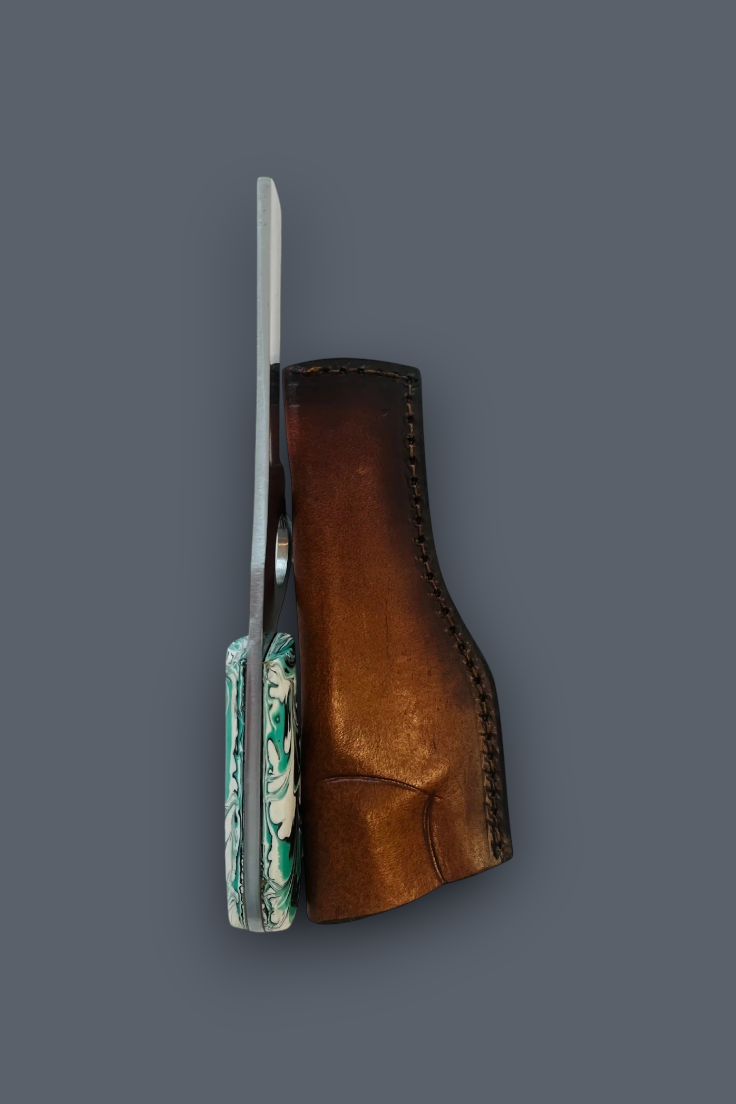 A folding pocket knife with a silver blade and a green, white, and blue marbled handle, shown next to its brown leather sheath on a solid dark gray background.