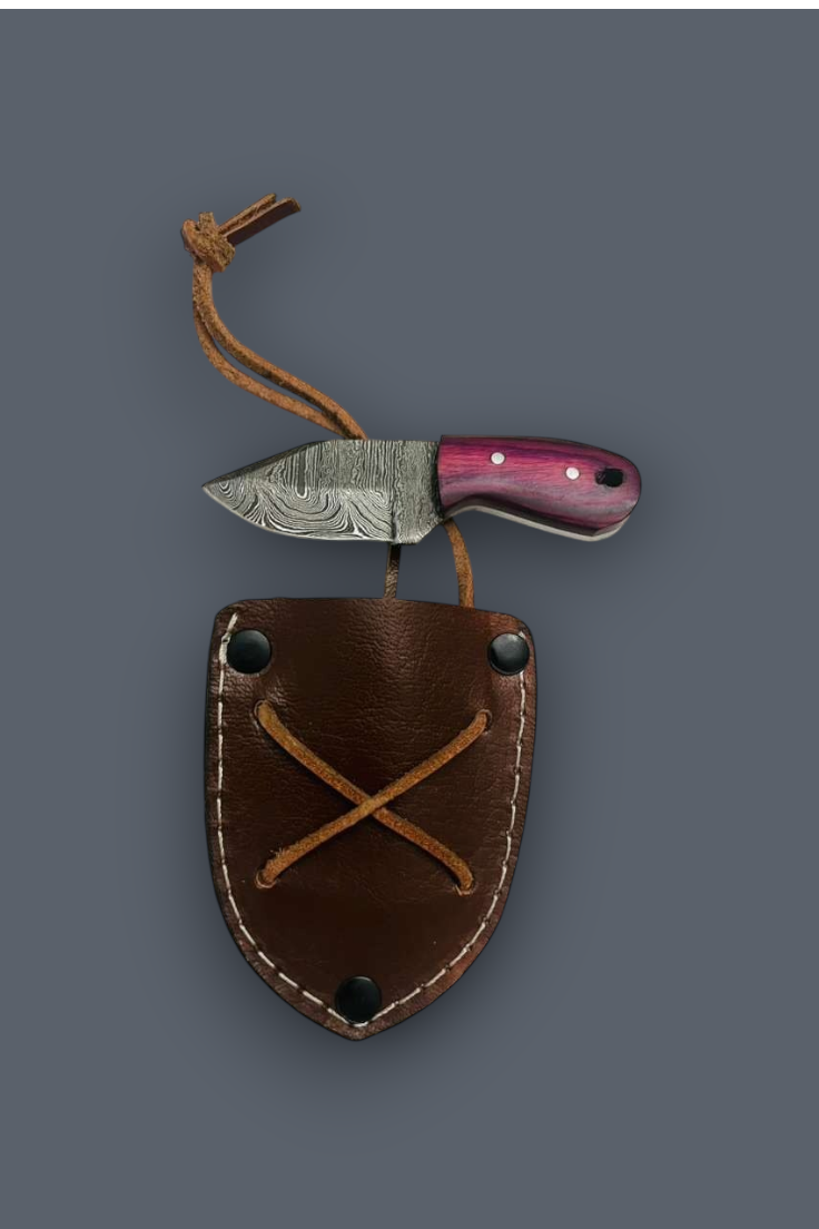A fixed-blade knife with a patterned steel blade and a pinkish-purple handle, shown resting on top of a brown leather sheath with a tan cord loop, against a solid dark gray background.