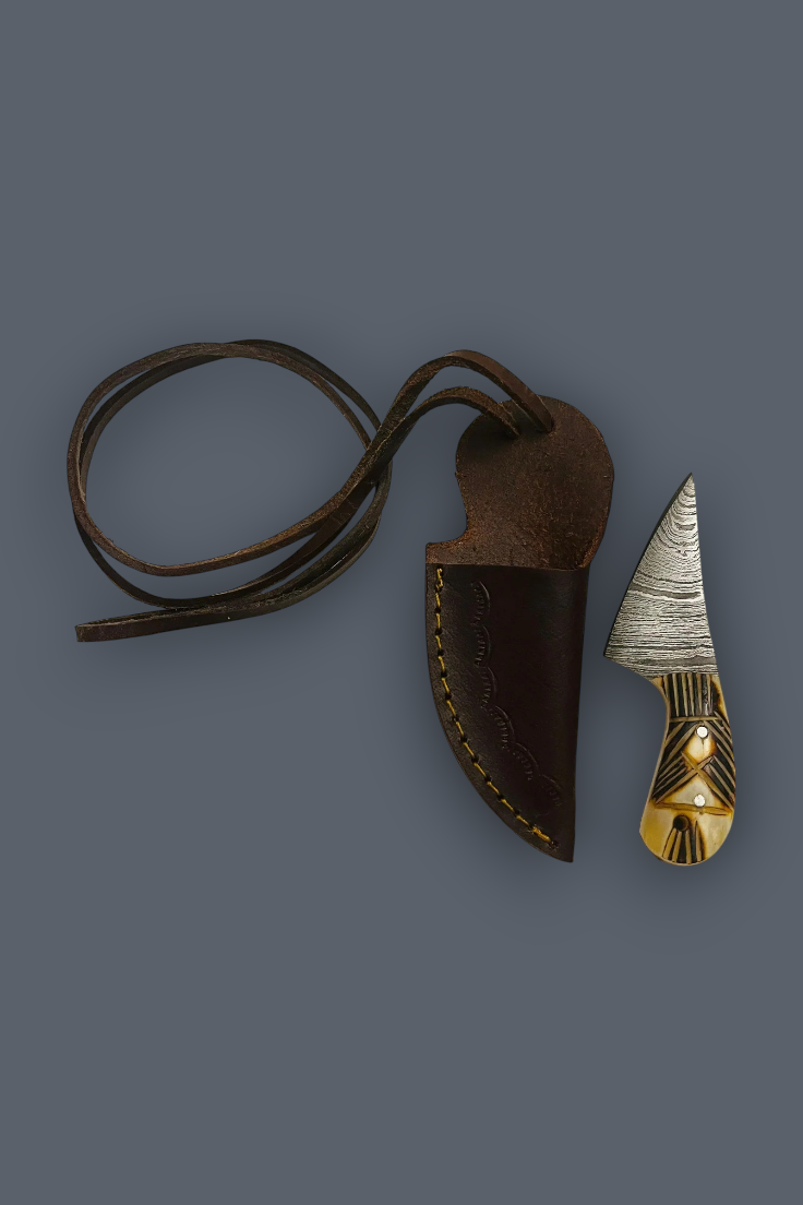 A fixed-blade knife with a textured silver blade and a carved gold-toned handle, shown next to its dark brown leather sheath with a matching leather lanyard on a solid dark gray background.