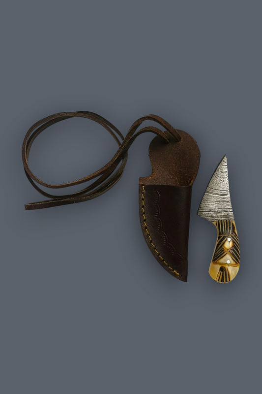 A fixed-blade knife with a textured silver blade and a carved gold-toned handle, shown next to its dark brown leather sheath with a matching leather lanyard on a solid dark gray background.