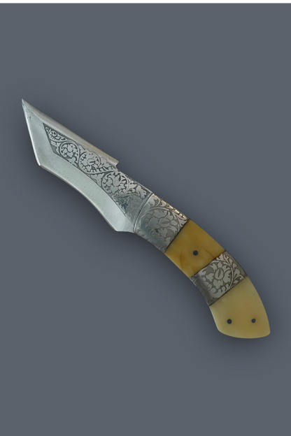 A decorative folding pocket knife with a patterned steel blade and a handle made of yellow bone and patterned silver inlays, shown on a solid dark gray background.