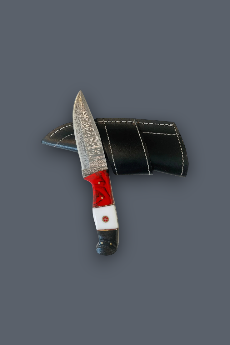 A custom fixed-blade knife with a patterned steel blade, red and white handle, and a black leather sheath, displayed on a solid dark gray background.