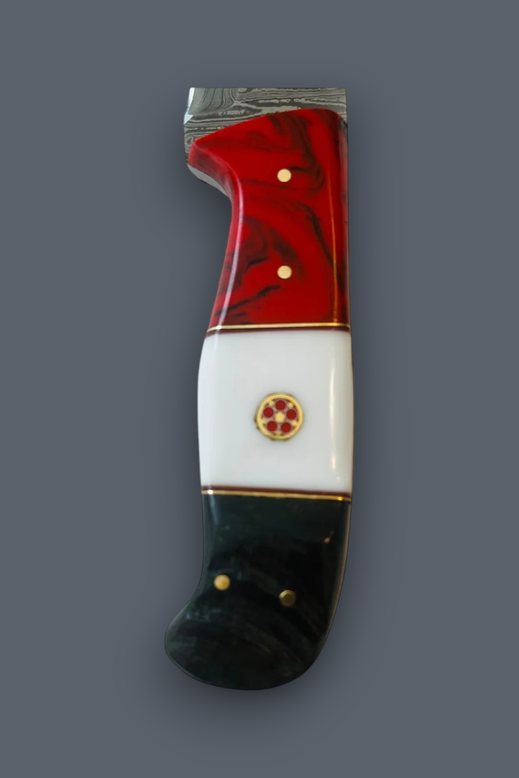 A decorative knife handle with a red and black marbled top section, a white middle section, and a black bottom section, accented with gold-colored pins and a central emblem, set against a solid gray background.