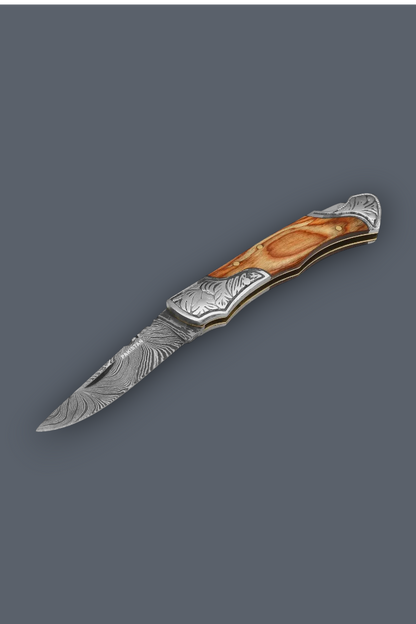 A folding pocket knife with a Damascus steel blade and an ornate handle made of layered brown wood and silver metal, shown on a solid dark gray background.