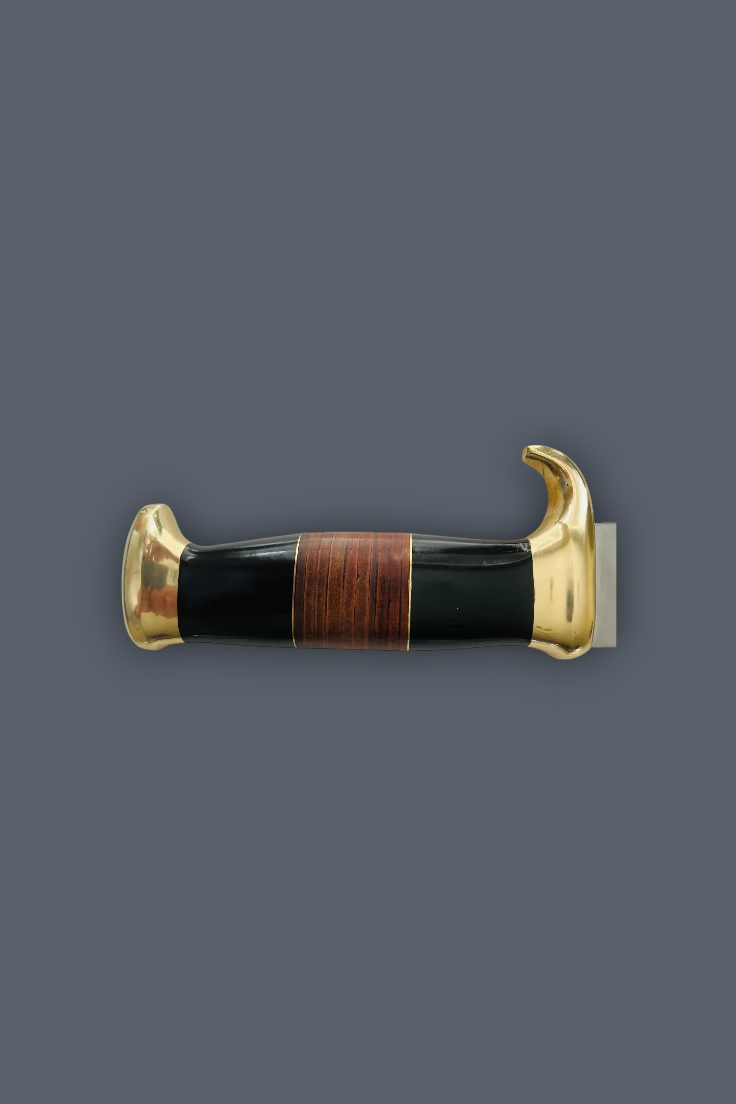 A decorative dagger or letter opener with a polished black handle, a central brown wood inlay, and ornate gold-toned metal ends, shown against a solid dark gray background.