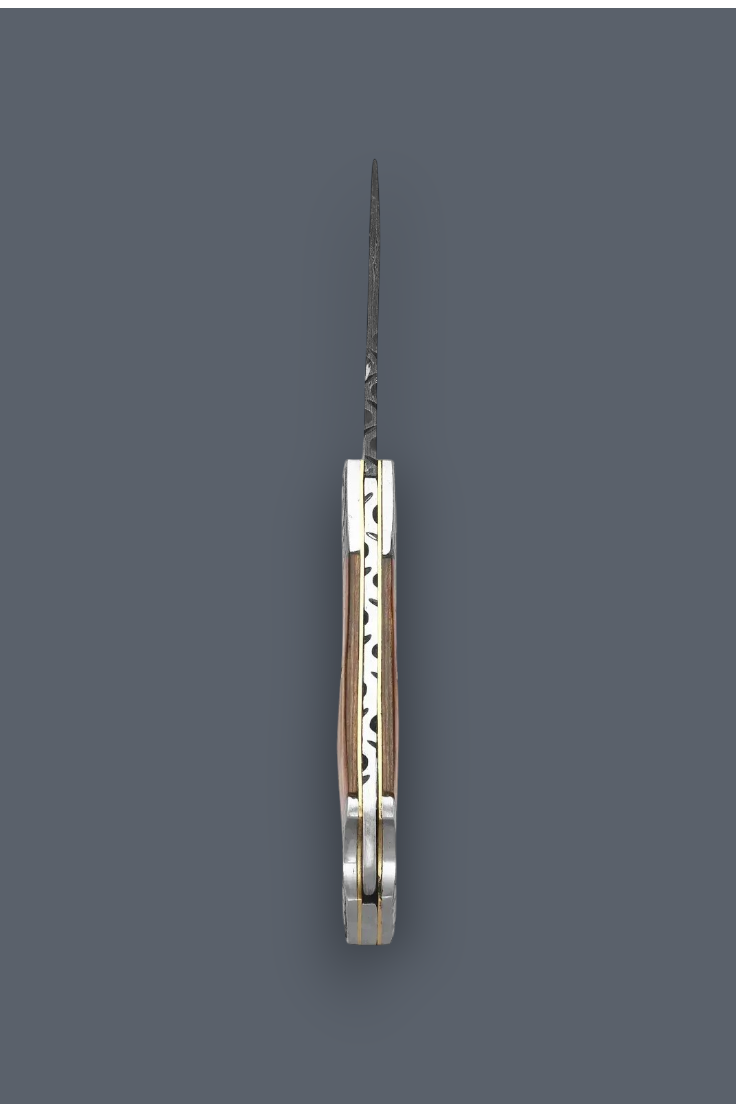 A folding pocket knife shown vertically in its open position, featuring a patterned steel blade and a silver-toned metal handle with a warm wood inlay, set against a solid dark gray background.