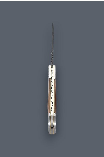A folding pocket knife shown vertically in its open position, featuring a patterned steel blade and a silver-toned metal handle with a warm wood inlay, set against a solid dark gray background.