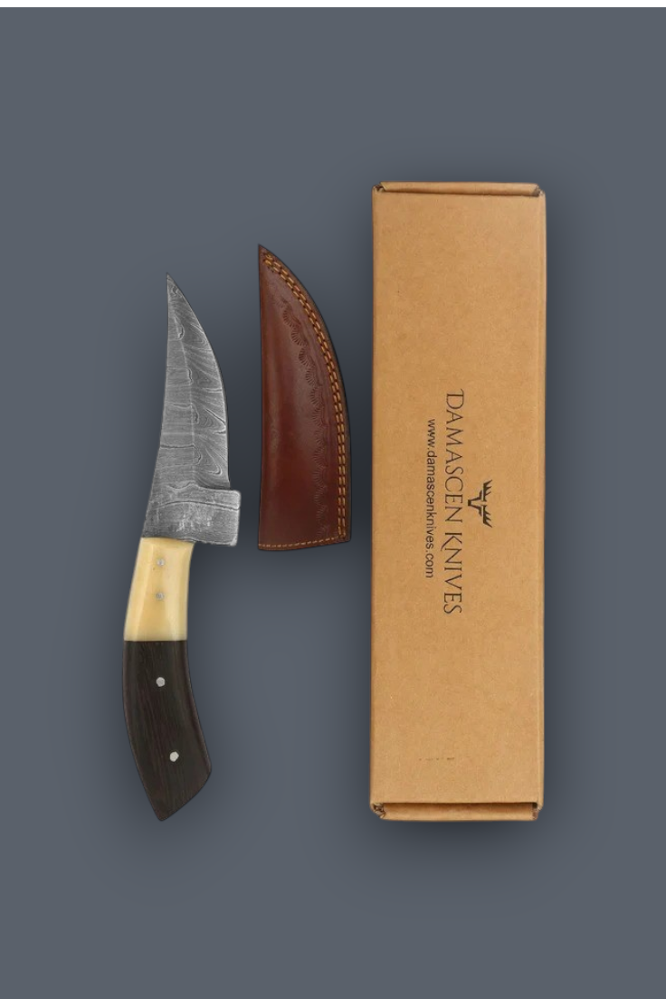 Damascen Knives knife with a patterned steel blade, dark wood handle, and brown leather sheath, displayed next to its kraft paper packaging box on a dark gray background.