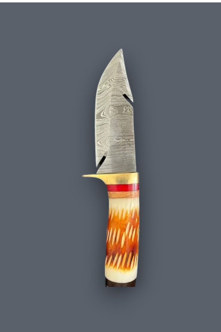 A fixed-blade knife with a patterned Damascus steel blade, a brass guard, and a carved handle made from natural horn with orange, brown, and cream tones, shown against a solid dark gray background.