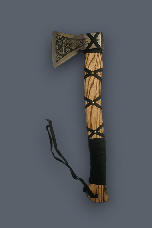 A decorative hand axe with a silver-toned engraved metal head, a light wood handle, black woven bands, and a black wrapped grip, shown on a plain dark gray background.