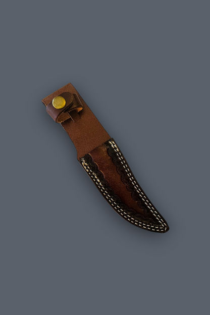 A brown leather knife sheath with decorative contrast stitching and a brass snap fastener, shown diagonally on a solid dark gray background.