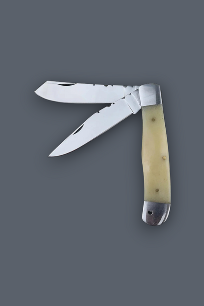 A classic folding pocket knife with two partially serrated stainless steel blades, featuring a cream-colored bone handle with silver-toned metal bolsters, set against a solid dark gray background.