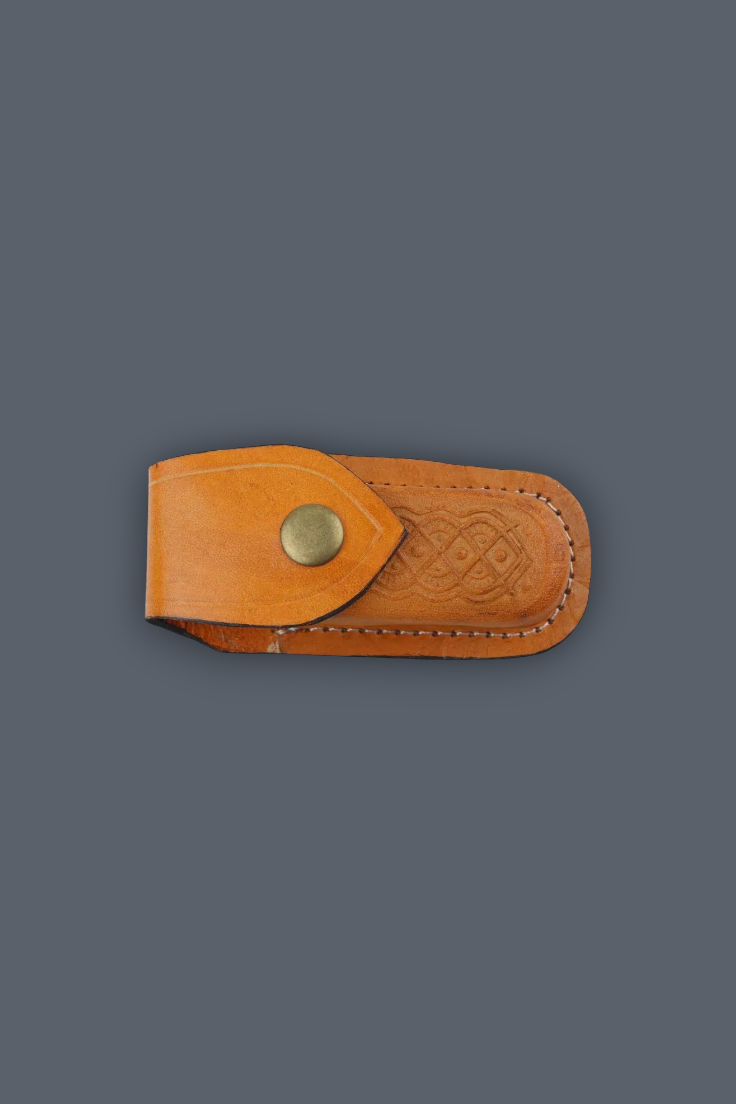 A tan leather knife sheath with a brass snap button and embossed Celtic knot pattern, shown on a solid dark gray background.