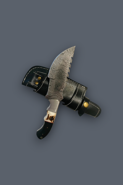 A fixed-blade knife with a patterned steel blade, black handle, and brass guard, shown crossed over a black leather sheath on a solid dark gray background.