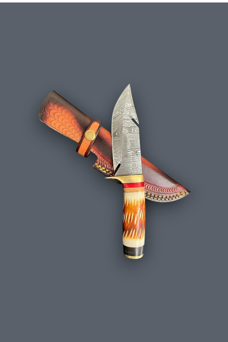 A decorative fixed-blade knife with a patterned steel blade, a carved handle in orange, cream, and black, and a matching brown sheath with red and white patterned detailing, shown on a solid dark gray background.