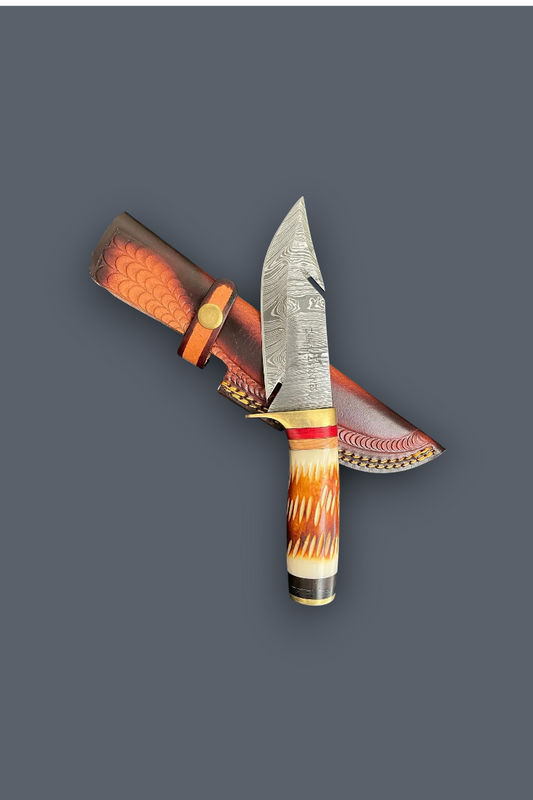 A decorative fixed-blade knife with a patterned steel blade, a carved handle in orange, cream, and black, and a matching brown sheath with red and white patterned detailing, shown on a solid dark gray background.