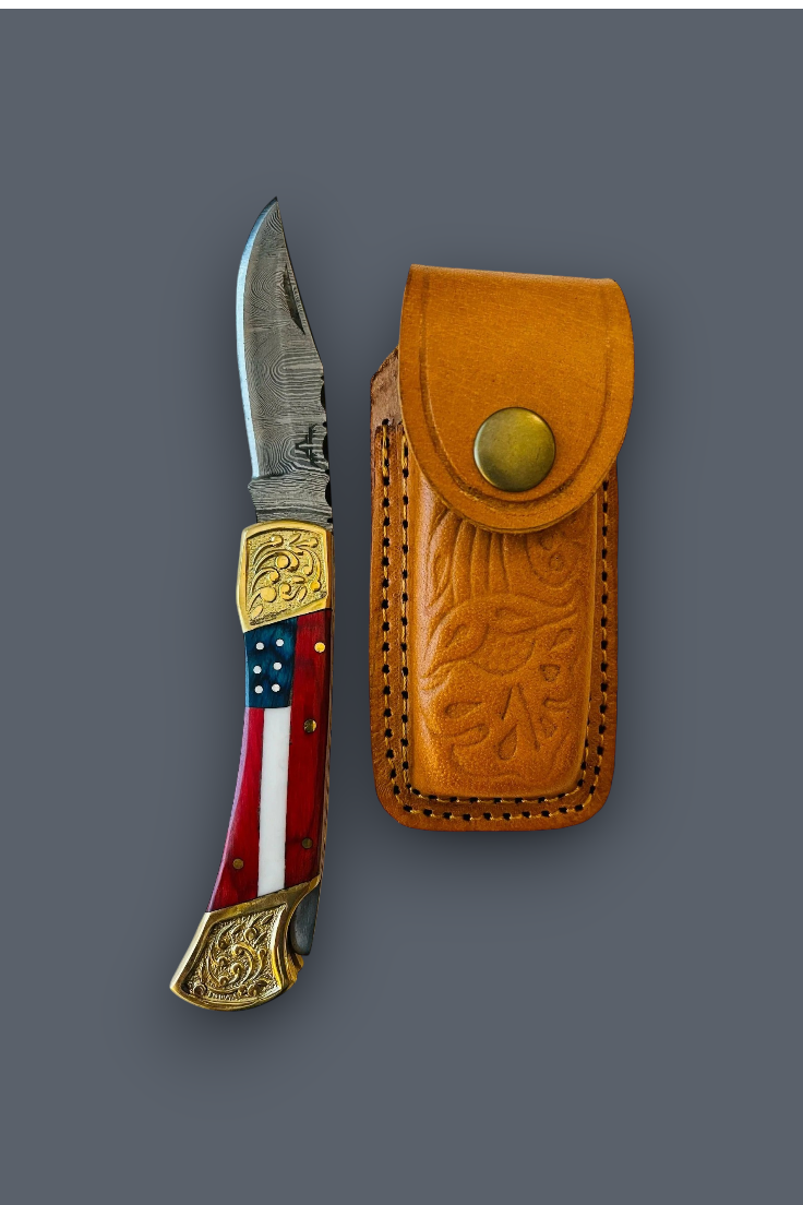 A folding pocket knife with a patterned red, white, and blue handle and gold-toned metal accents, shown next to its tan leather sheath on a solid dark gray background.
