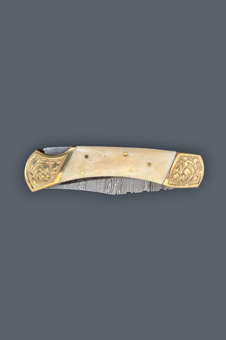 A folding pocket knife with a cream-colored bone handle and ornate gold-toned metal end caps, shown open against a solid dark gray background.